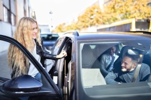 person getting into car with other people already in it