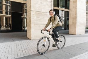 man riding on bike in business clothes with headphones