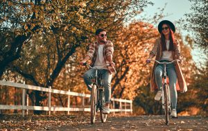 couple riding bikes down the road during autumn